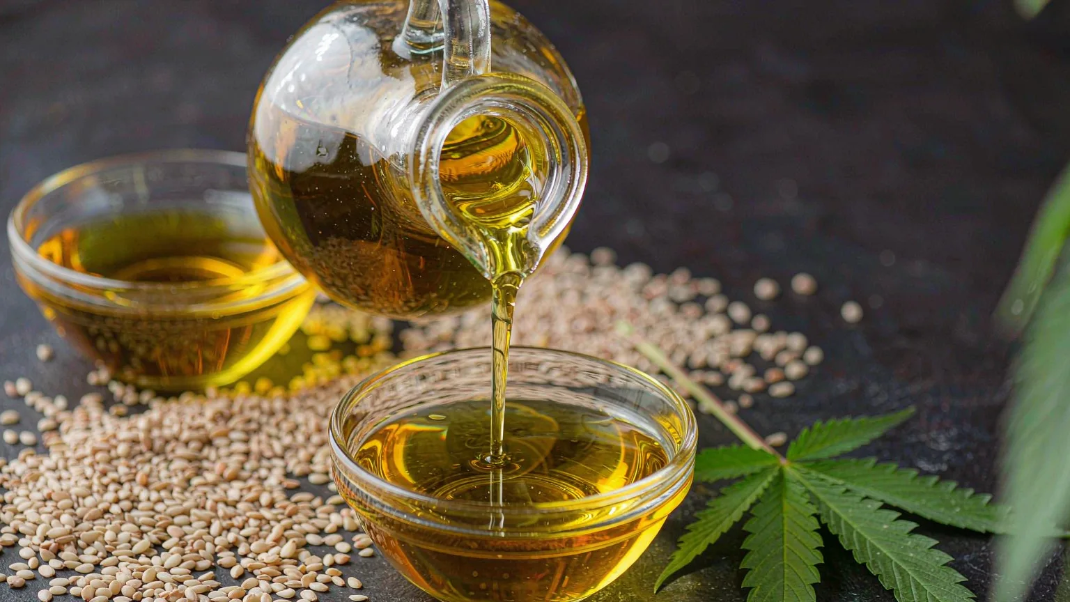 Hanfsamenöl Omega-3 und Omega-6: das ausgewogene Verhältnis verstehen 7 Golden hemp seed oil poured into a glass bowl with hemp hearts and a fresh hemp leaf